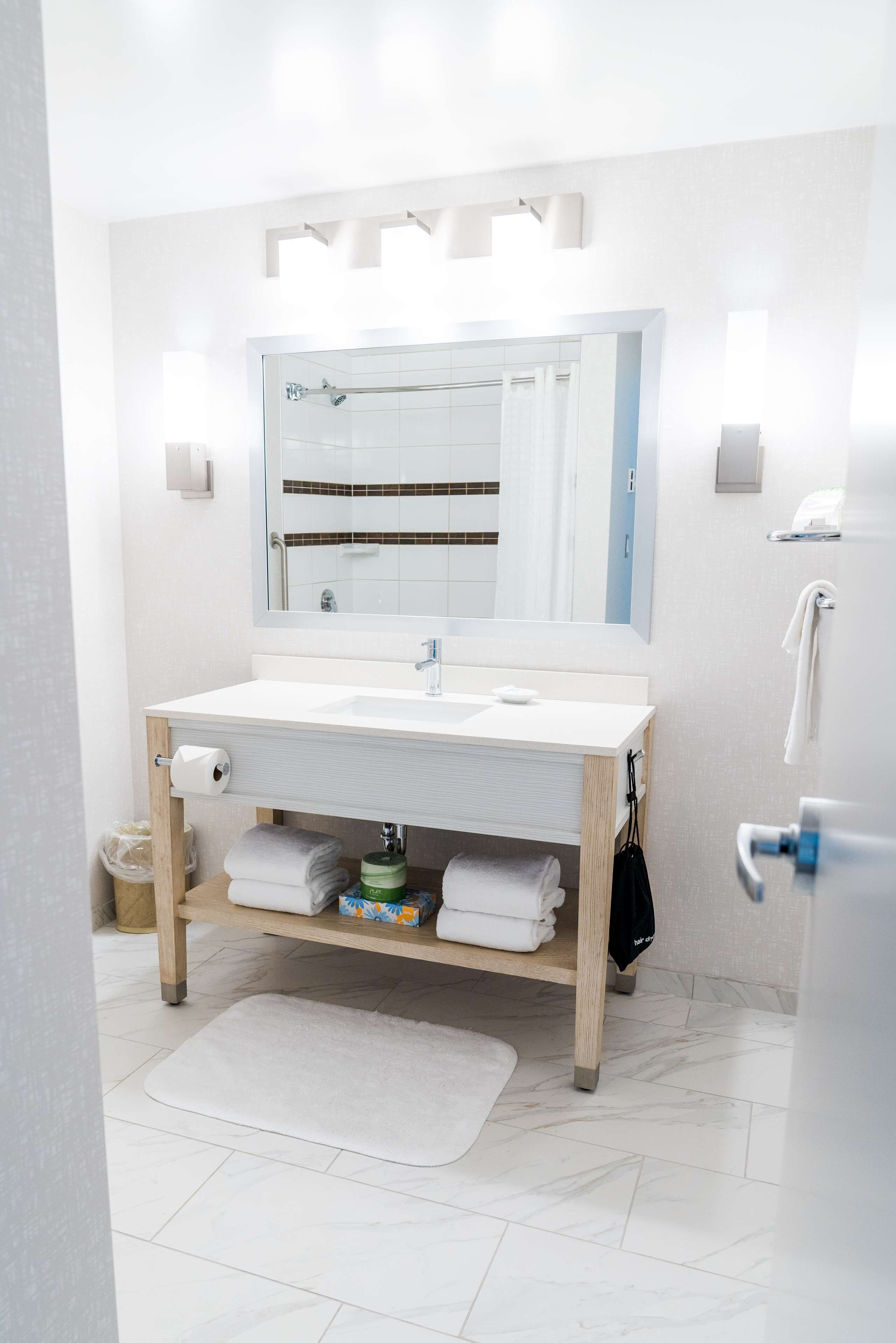A modern bathroom with a white sink, mirror, and towel rack.