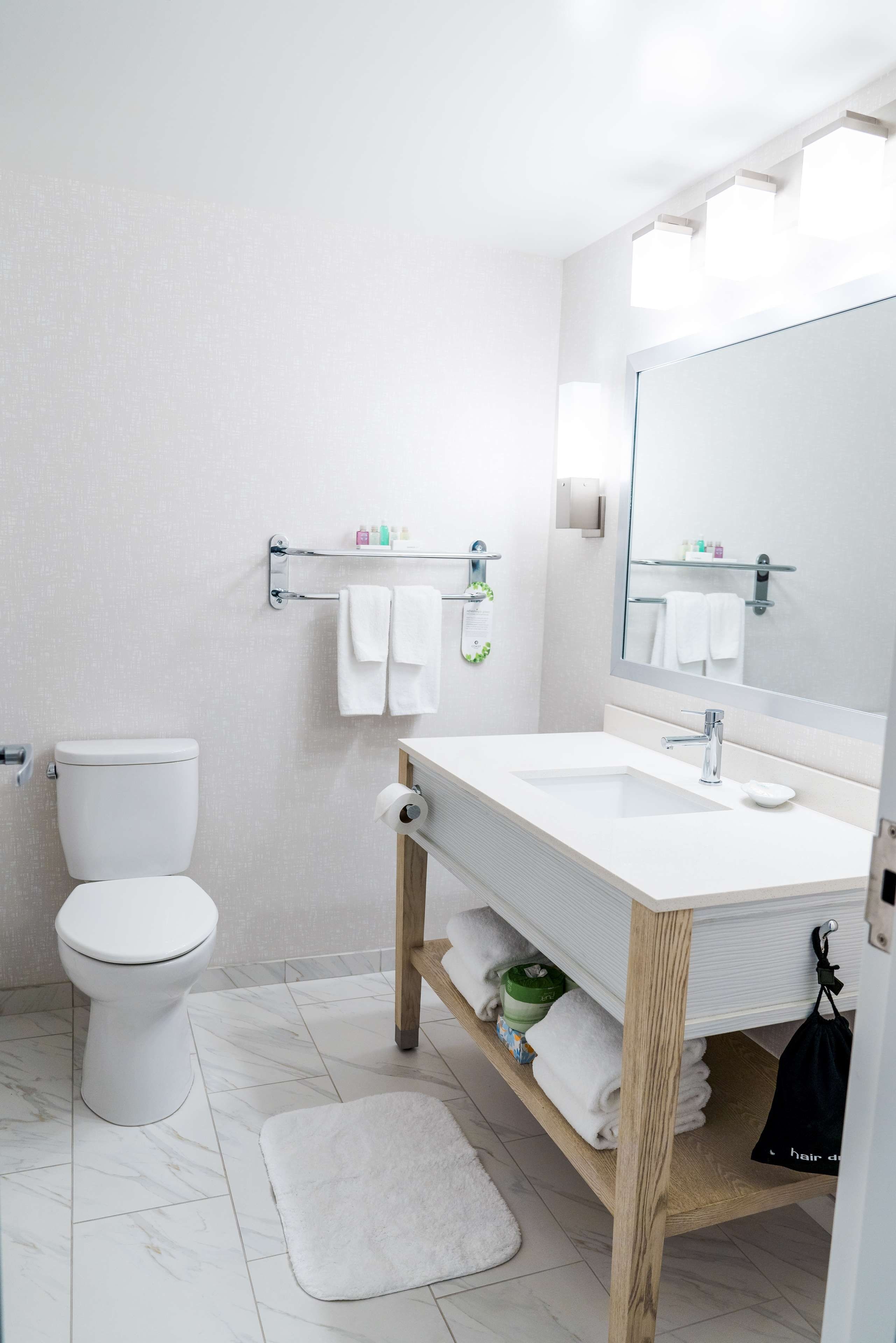 Un baño moderno con inodoro, lavamanos y espejo.