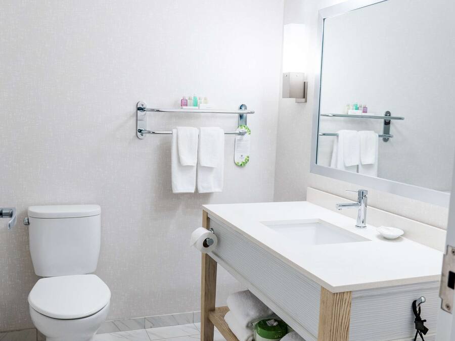 A modern bathroom with a toilet, sink, and mirror.