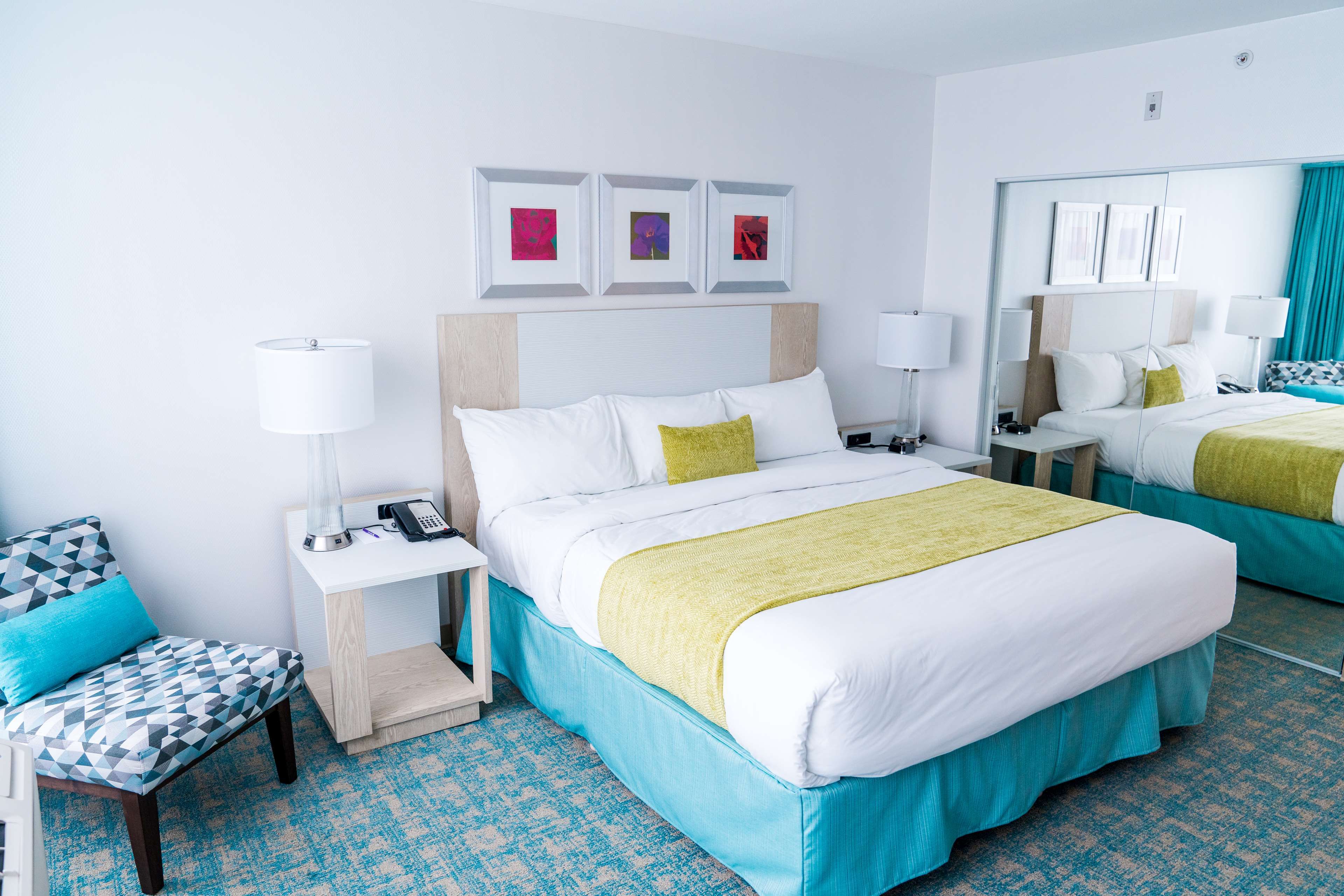 A hotel room with a large bed, two bedside tables, a chair, and a mirror.