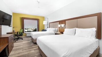 A hotel room with two beds, a desk, a chair, a TV, and a window with a view.