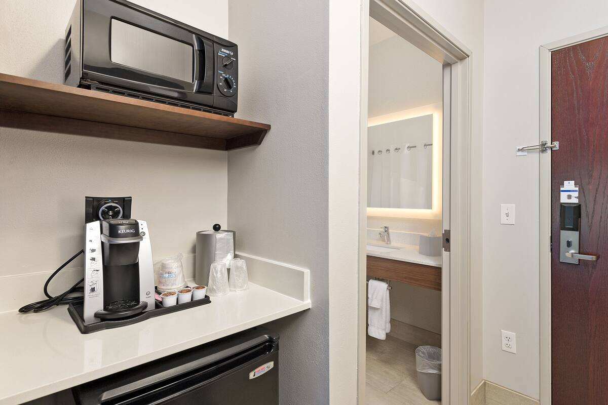 A kitchenette with a coffee maker, microwave, and a small refrigerator.