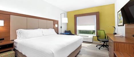 Habitación de hotel con una cama grande, un escritorio, una silla, un televisor y una ventana con vistas.