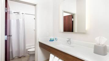 A bathroom with a white sink, a mirror, a towel rack, and a shower curtain.