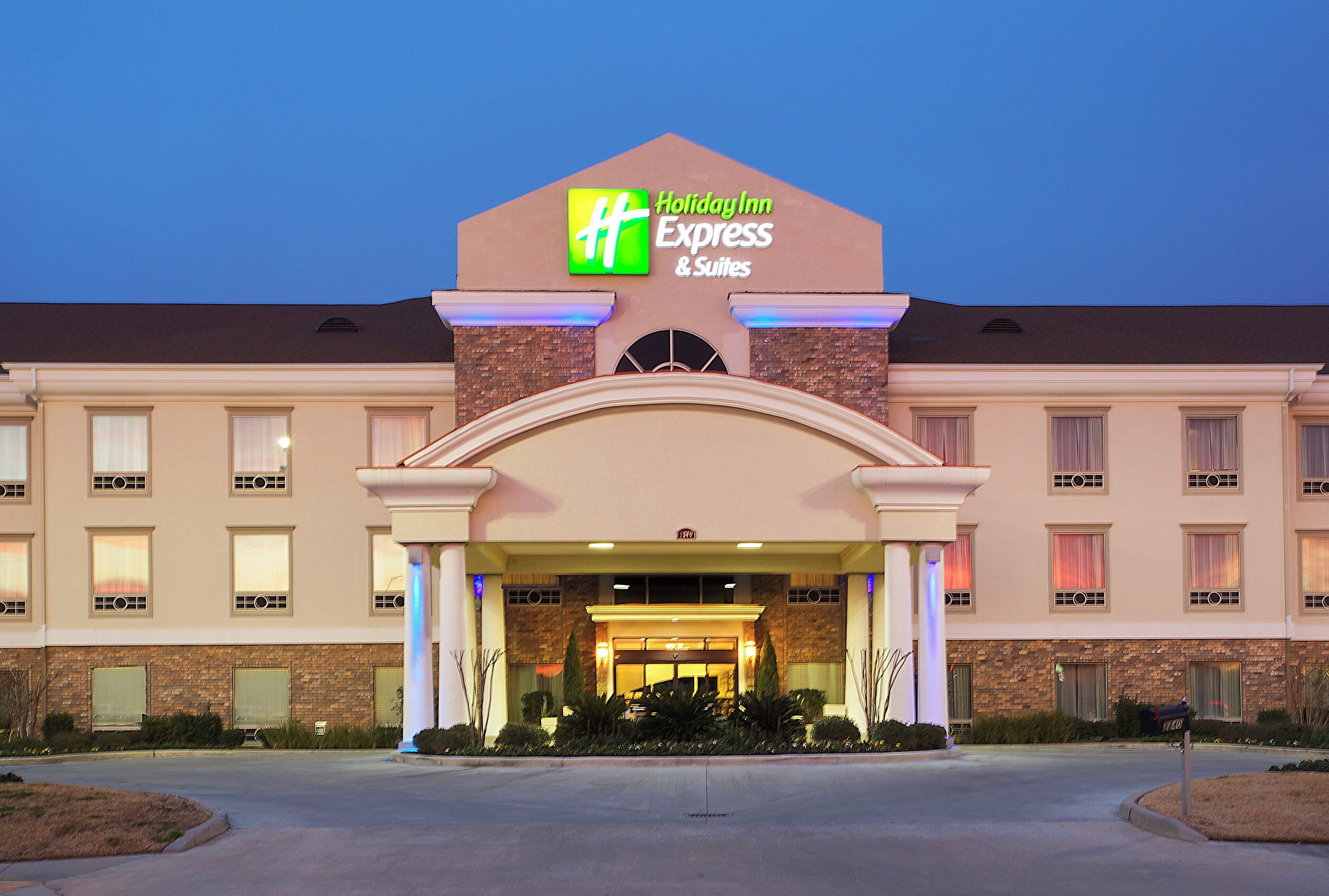 Un hotel Holiday Inn Express & Suites con fachada de ladrillo, múltiples ventanas y una entrada bien iluminada.