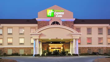 Un hotel Holiday Inn Express & Suites con fachada de ladrillo, múltiples ventanas y una entrada bien iluminada.