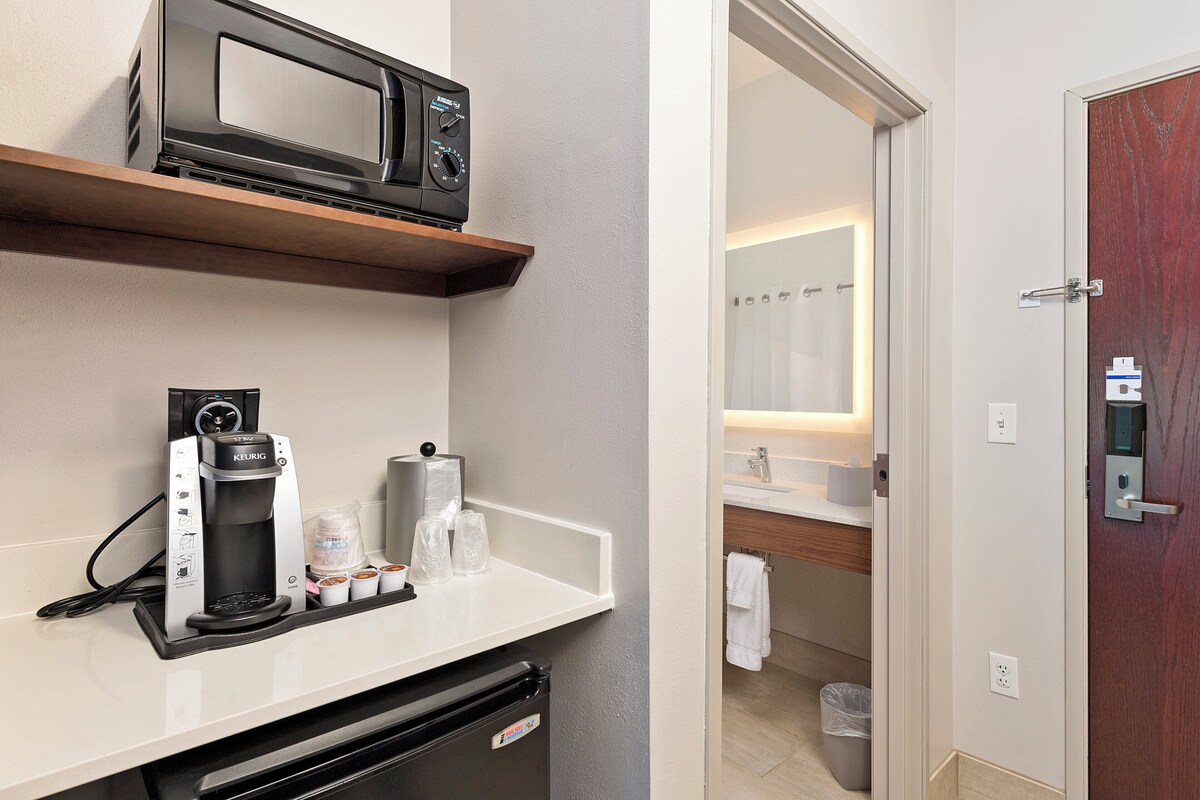 A kitchenette with a coffee maker, microwave, and storage containers.
