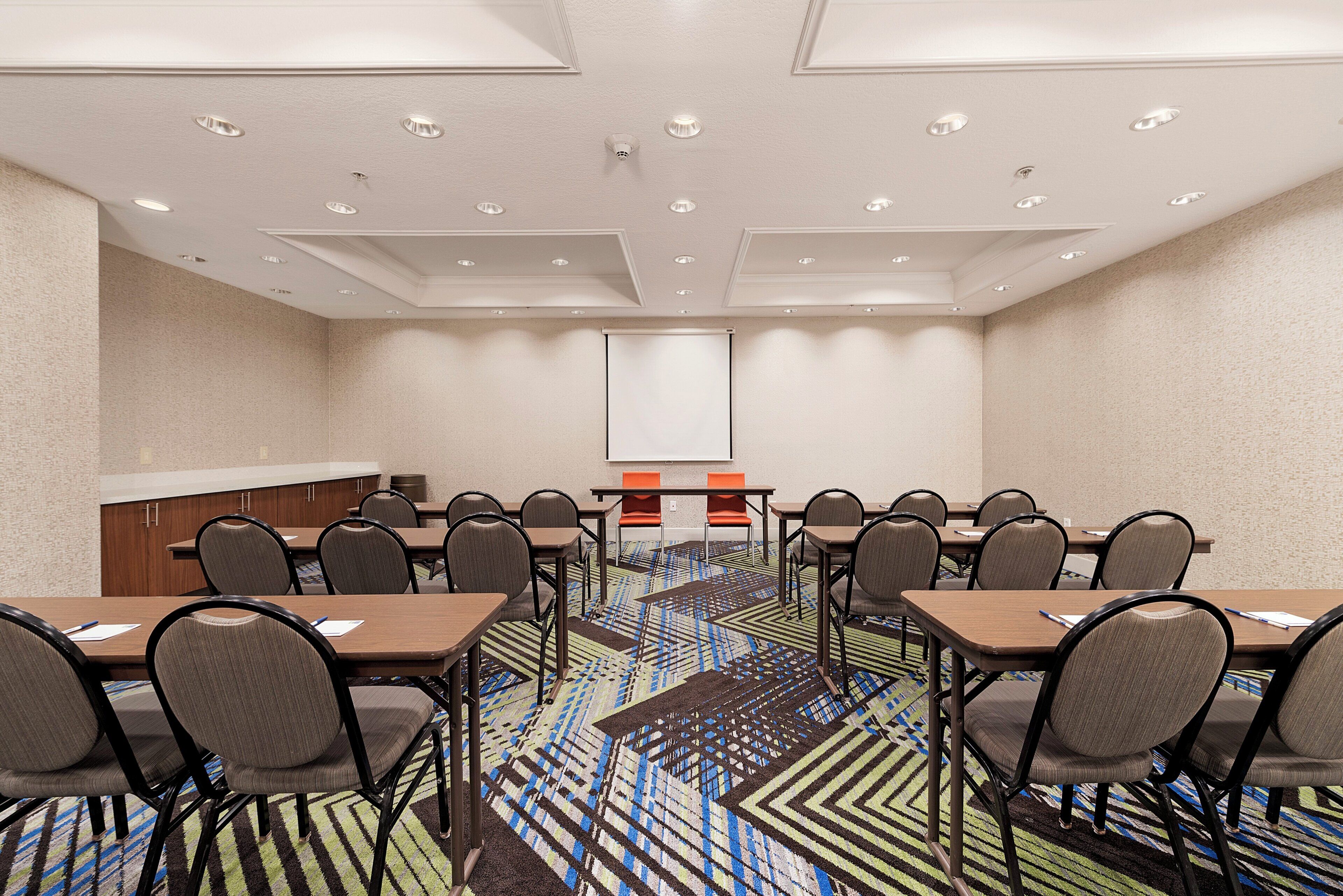 Un salón de conferencias con una pizarra, varias mesas y sillas.