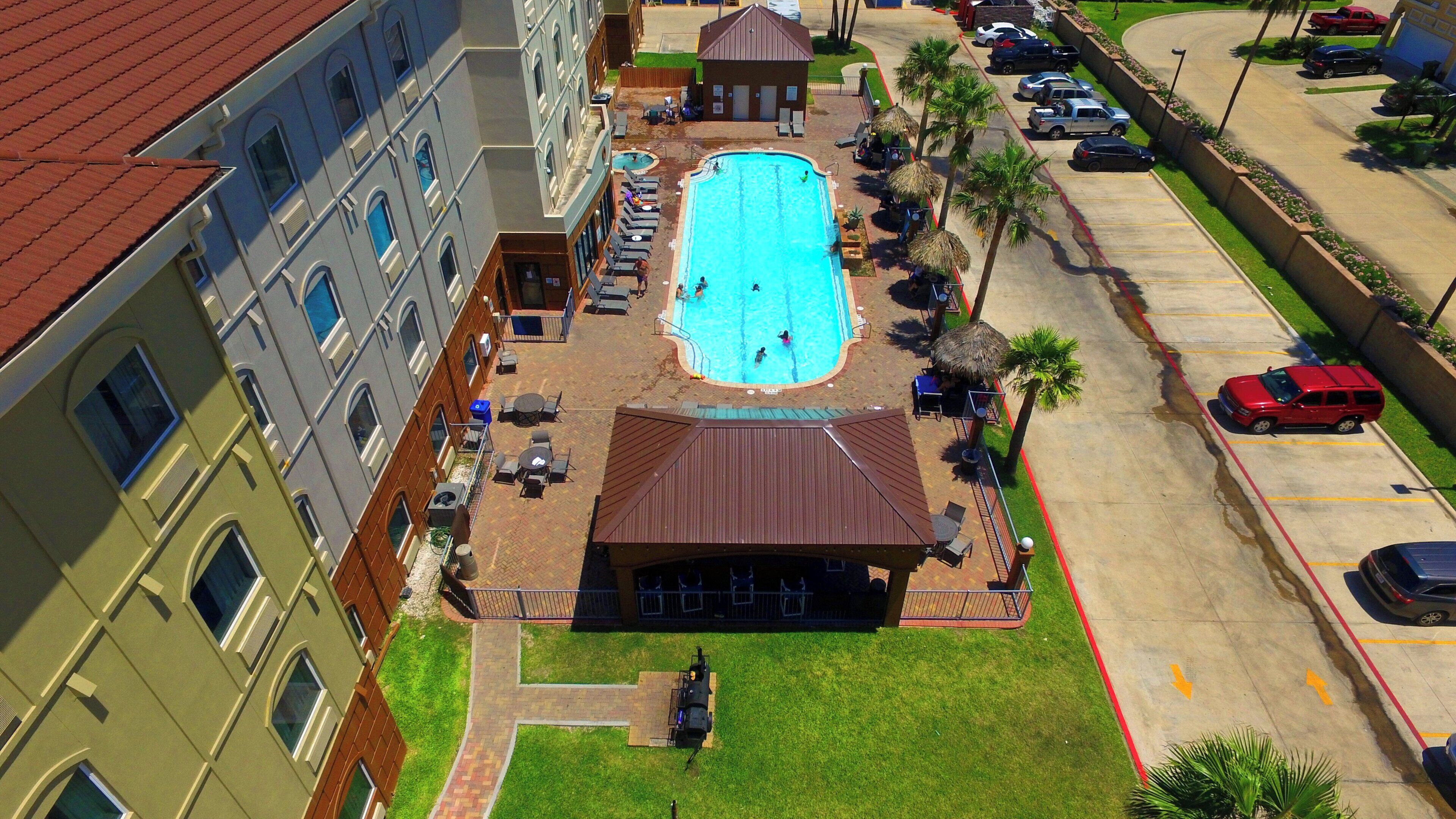 A swimming pool surrounded by lounge chairs and umbrellas, with a building adjacent to it.