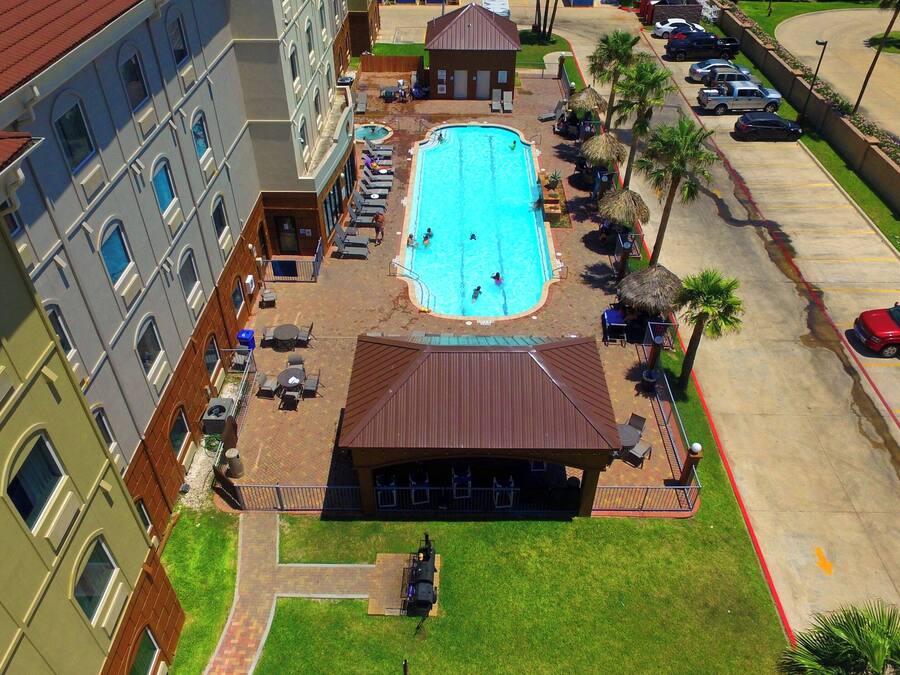 A swimming pool surrounded by lounge chairs and umbrellas, with a building adjacent to it.