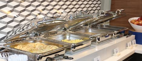 Una mesa de buffet con diversos alimentos y utensilios.