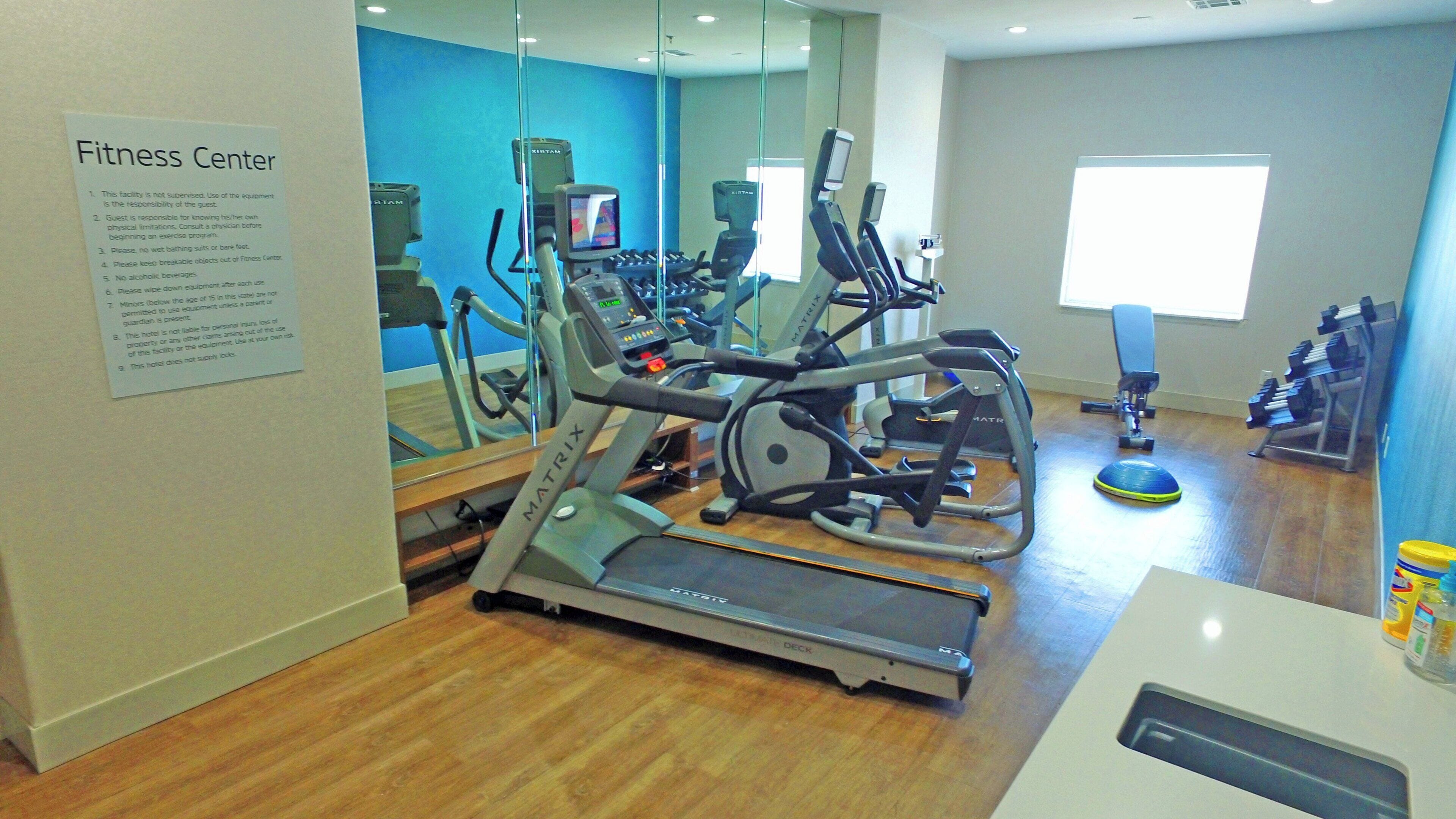 Un gimnasio con cintas de correr, elípticas y pesas libres.