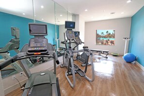 Un gimnasio con máquinas de cardio, vista a la piscina y pelotas de ejercicio.
