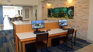 Un mostrador de recepción con dos monitores, un gran acuario y un diseño de interiores moderno.