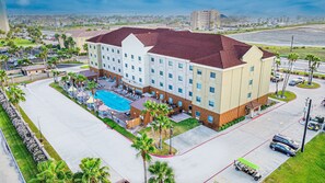 A hotel with a swimming pool, multiple floors, and a parking lot. - Holiday Inn Express Hotel & Suites South Padre Island by IHG (South Padre Island)