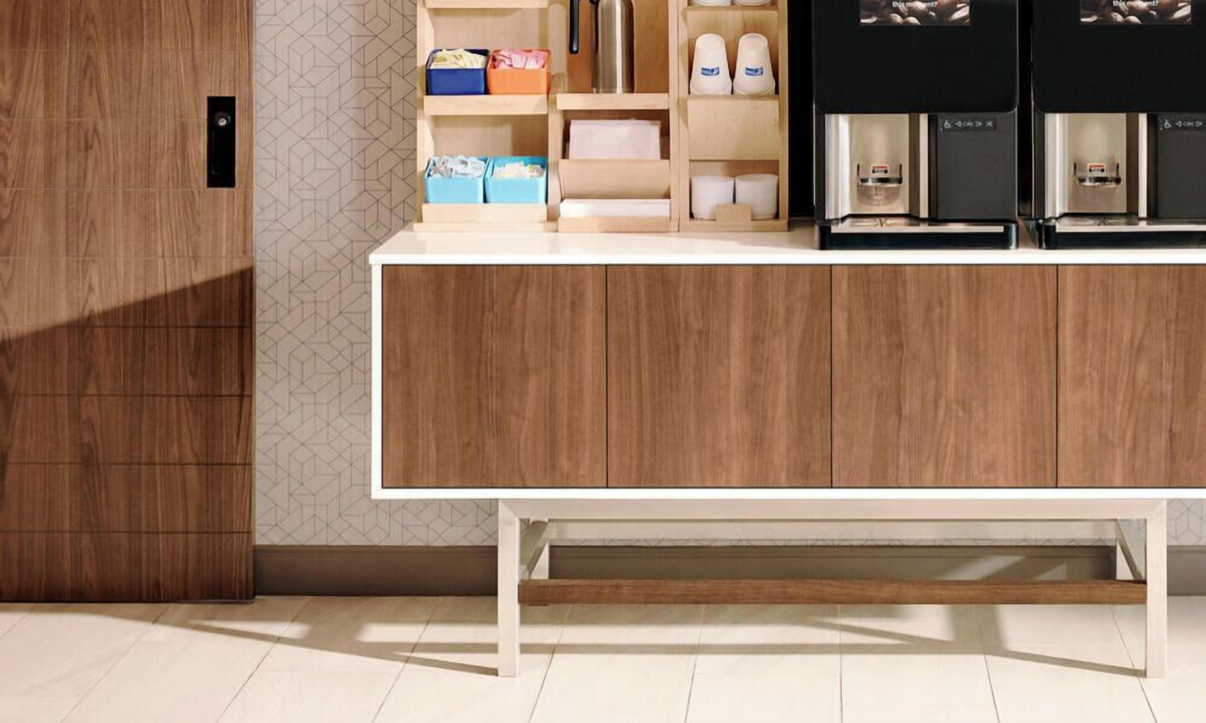 Una cocina moderna con armarios de madera, encimera blanca y electrodomésticos integrados.