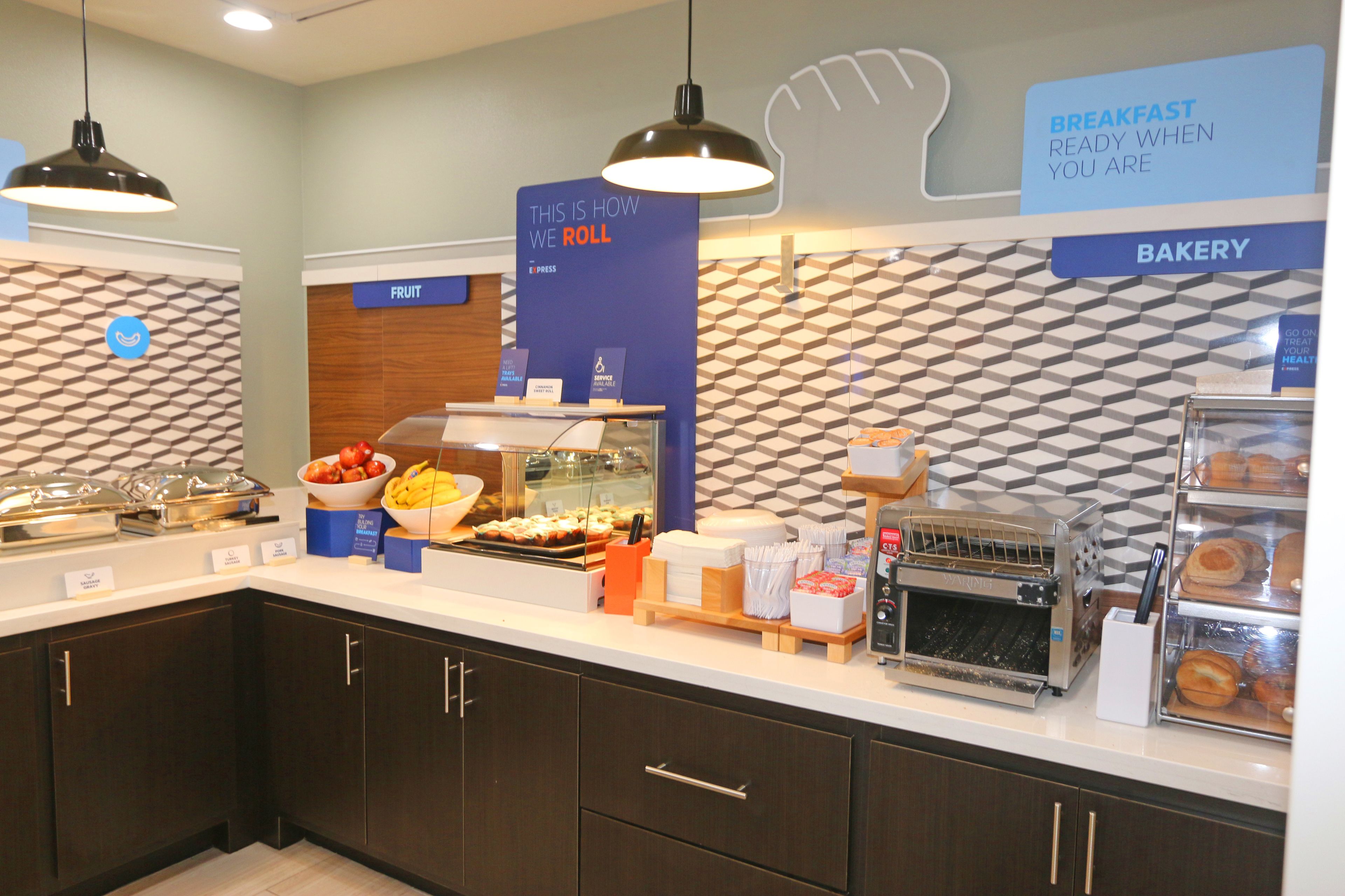 A breakfast buffet area with labeled sections for fruit, bakery, and a sign explaining the buffet service.