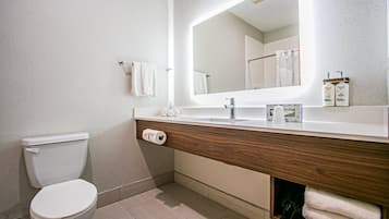 Moderni kylpyhuone, jossa on wc, peilillä varustettu pesuallas ja suihkutila.