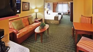 A hotel room with a sofa, a small table, a bed, and a TV. - Country Inn & Suites by Radisson, Springfield Downtown (Springfield)
