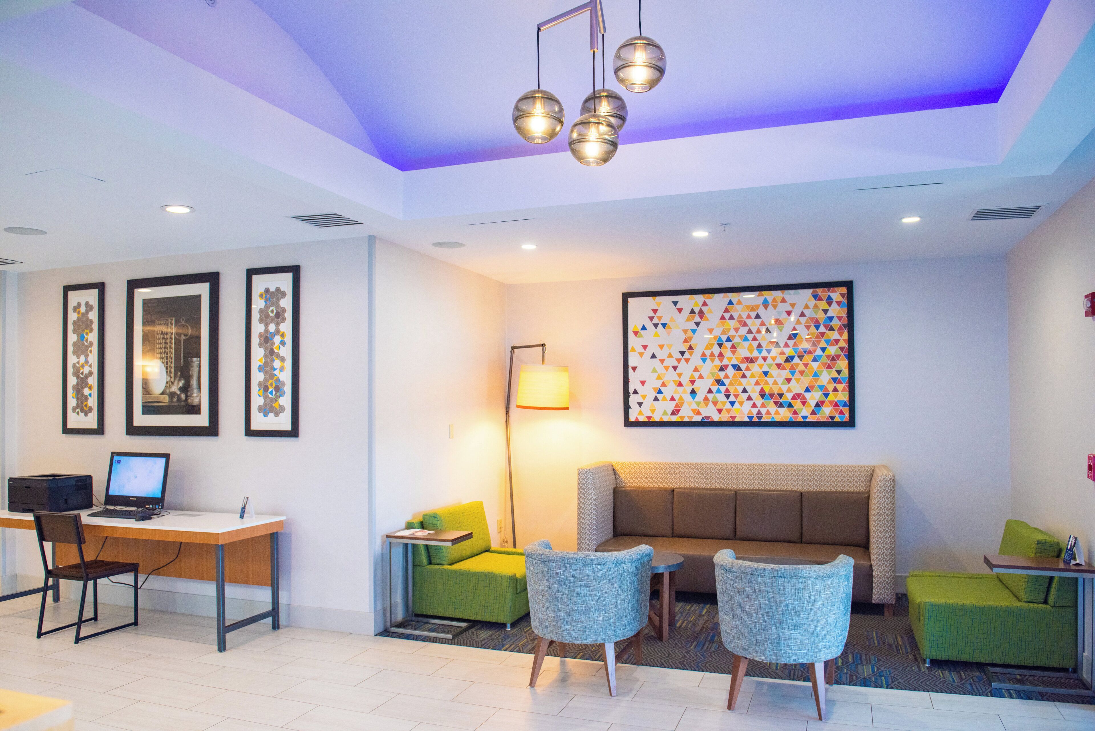 A modern lobby with a desk, chairs, a sofa, and artwork on the walls.