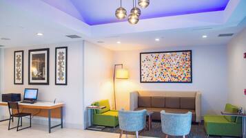A modern lobby with a desk, chairs, a sofa, and artwork on the walls.