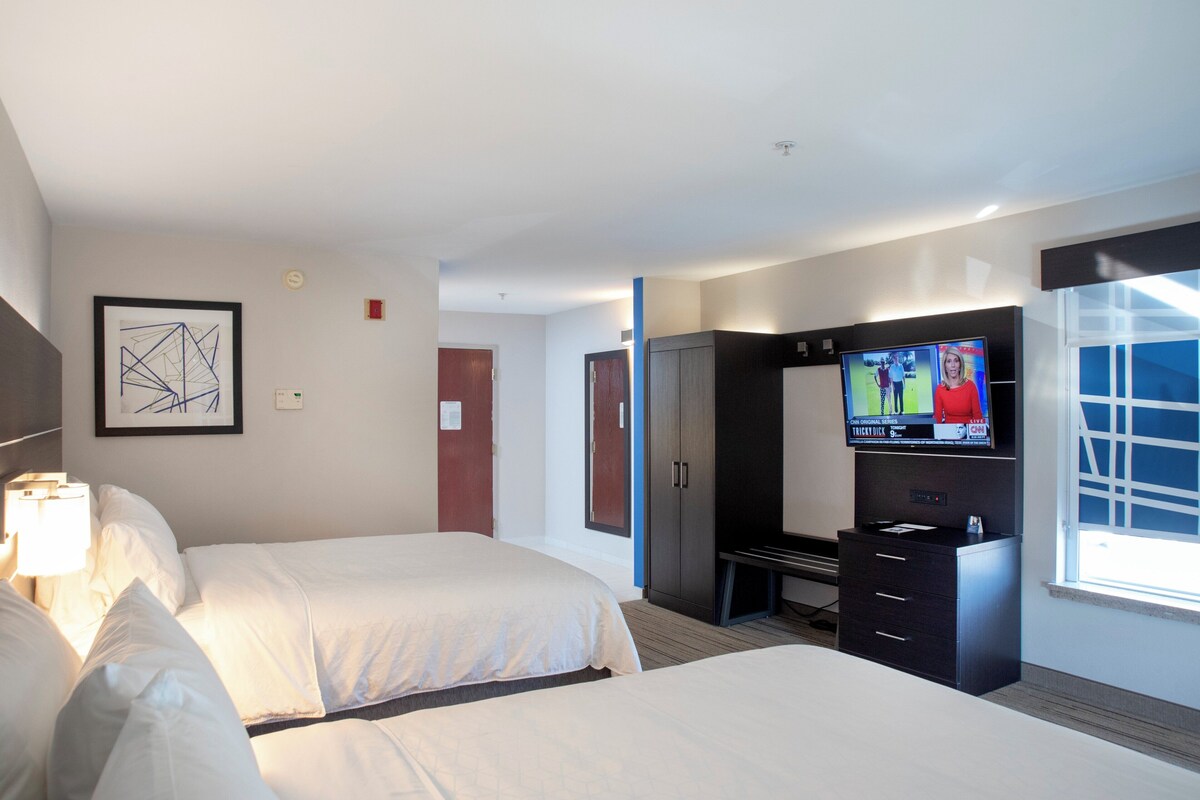 Une chambre d’hôtel avec deux lits, une télévision, un bureau et une armoire.