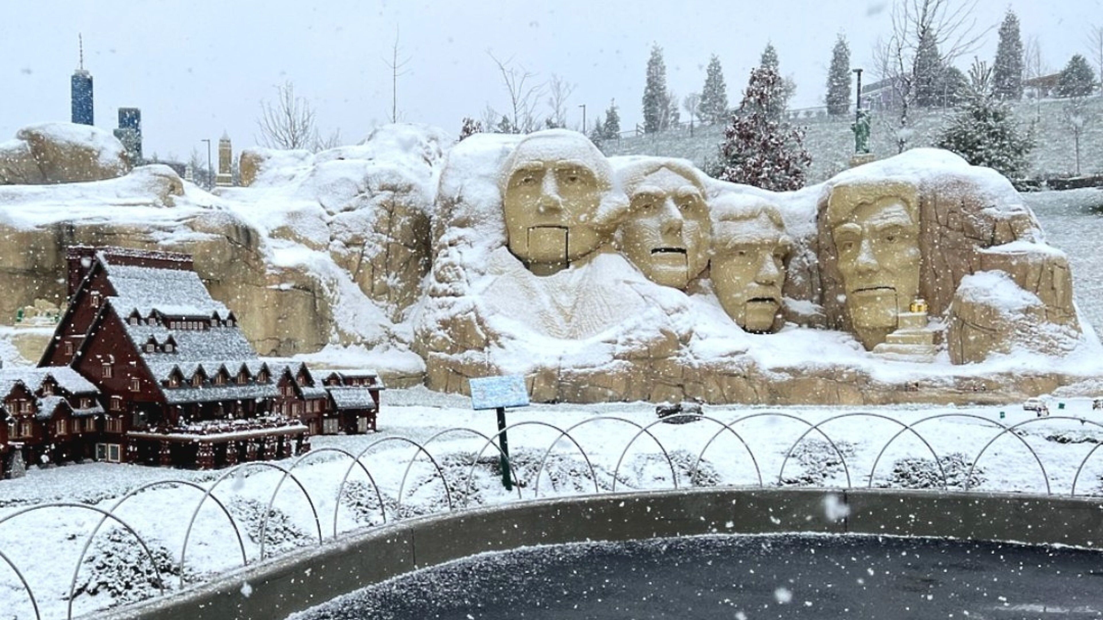 A snow-covered mountain with a large monument and a small building with a snow-covered roof.