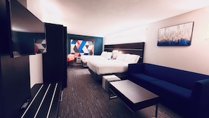 A hotel room with a bed, a sofa, a TV, a desk, and a wall with a geometric pattern. - Holiday Inn Express Hotel & Suites Chester by IHG (Chester)