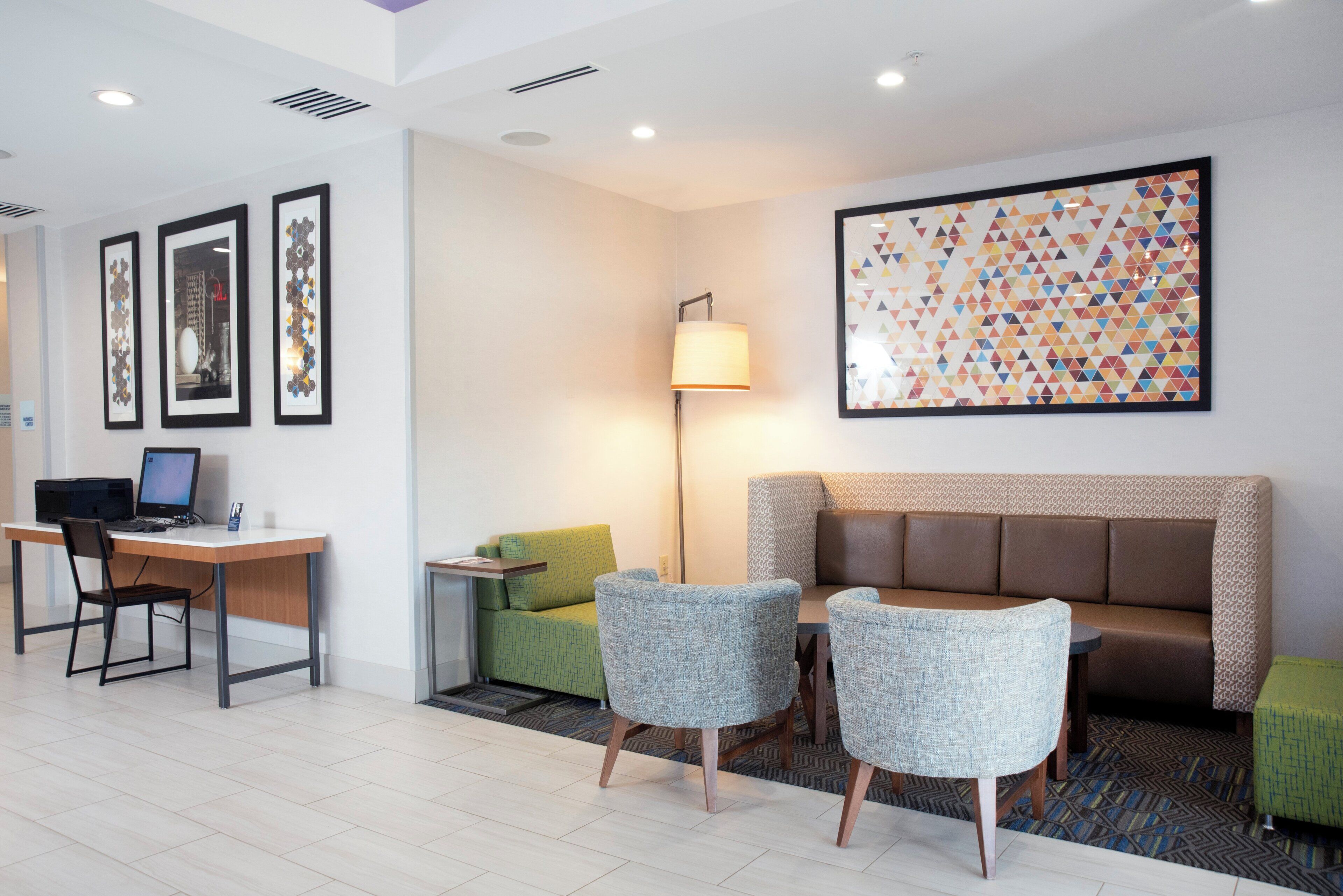 Un moderno vestíbulo de hotel con recepción, zona de estar y obras de arte en las paredes.