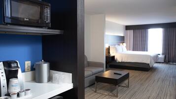 Habitación de hotel con kitchenette, cama, sofá y vista a la ciudad.