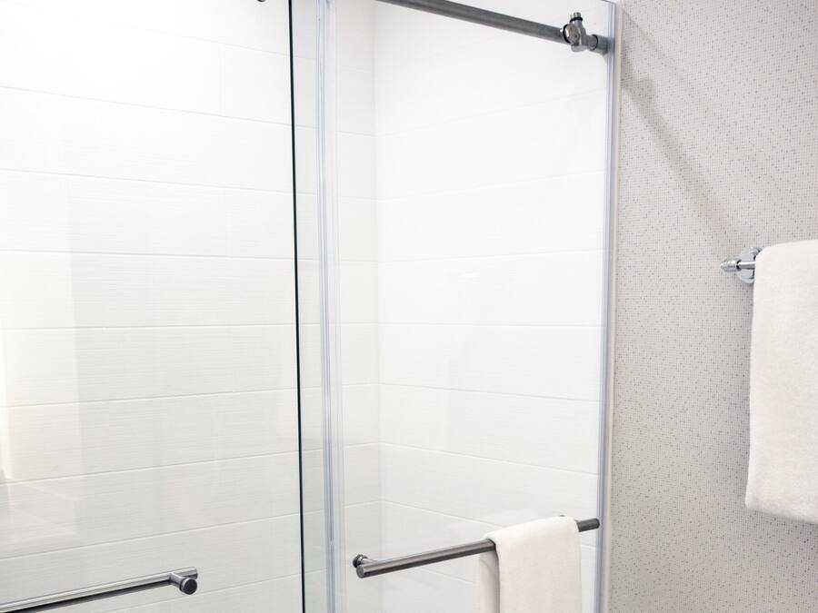 Une salle de bain moderne avec une douche à parois de verre, des toilettes blanches et un porte-serviettes.
