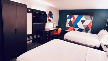 A hotel room with a bed, desk, chair, TV, and a geometric-patterned wall.