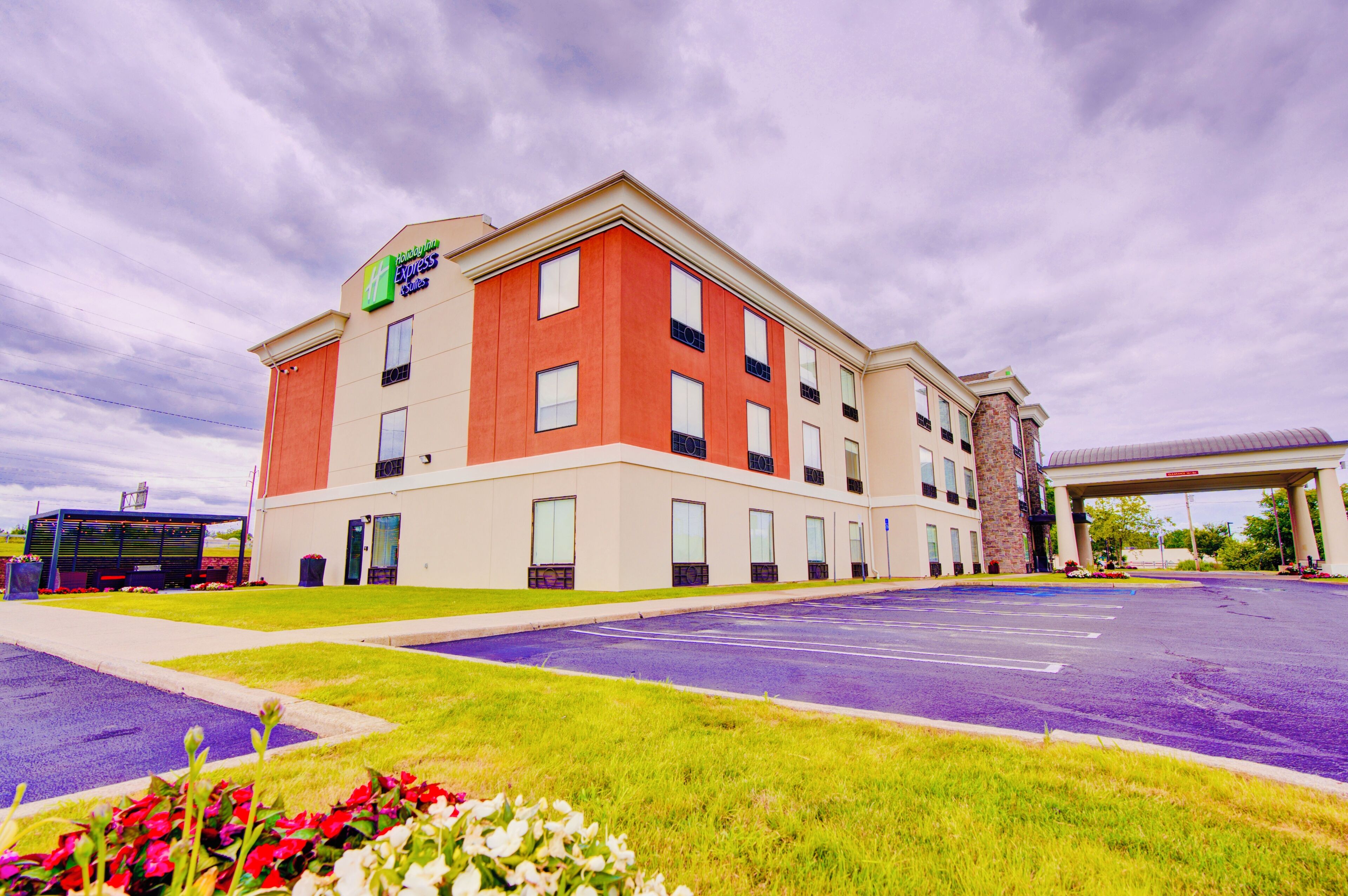 Un hotel Holiday Inn Express con un estacionamiento y una gasolinera al fondo.