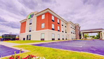 Un hotel Holiday Inn Express con un estacionamiento y una gasolinera al fondo.