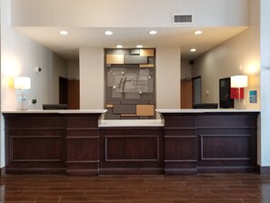 Un comptoir d’accueil au design moderne, une enseigne « Holiday Inn Express & Suites » et un intérieur propre et bien éclairé.