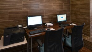 Un espace de travail équipé de deux ordinateurs de bureau, d’une imprimante et de deux chaises de bureau.