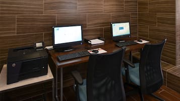 A workspace with two desktop computers, a printer, and two office chairs.