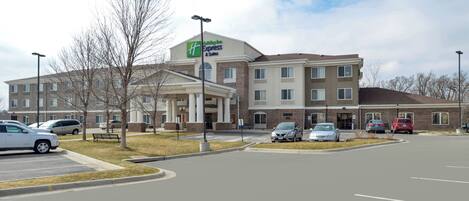 A Holiday Inn Express & Suites hotel with a parking lot and a clear sky.