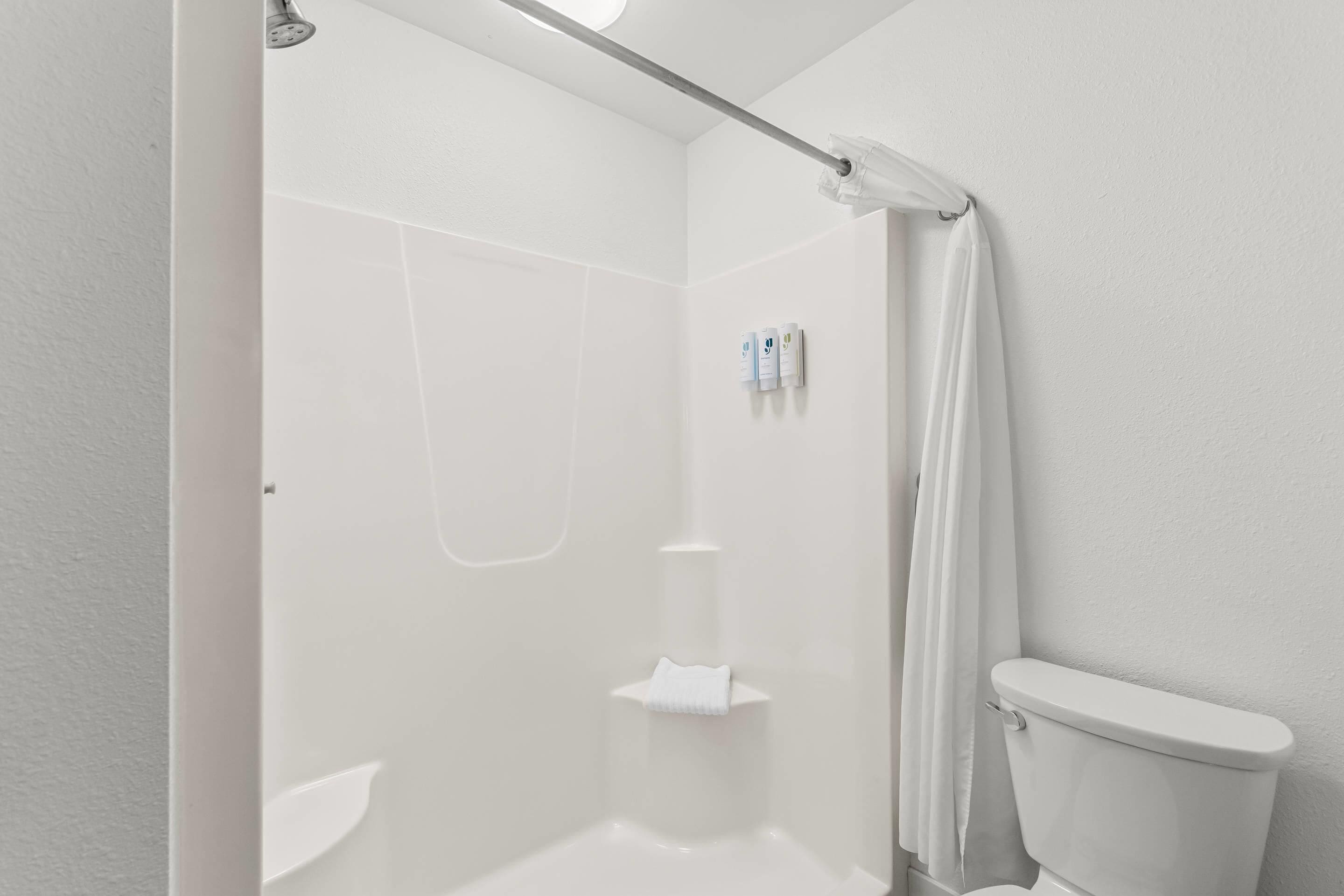 A bathroom with a shower, toilet, and a towel rack.