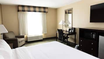 A hotel room with a large bed, a desk with a chair, a television, a mirror, and a window with curtains.