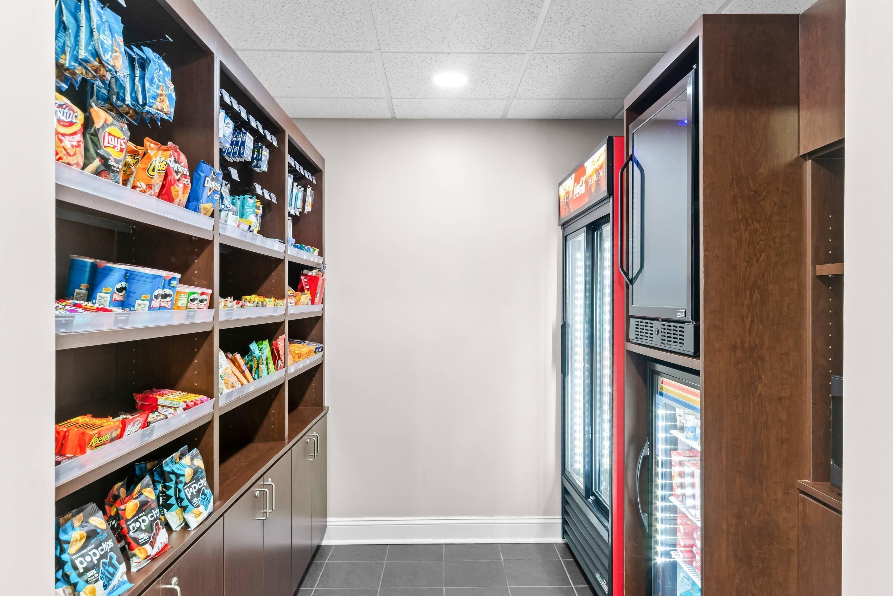 Un área de refrigerios y bebidas con estantes llenos de diferentes opciones y un refrigerador.