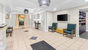A spacious living area with a fireplace, seating, and a television. - Country Inn & Suites by Radisson, Elizabethtown, KY (Elizabethtown)
