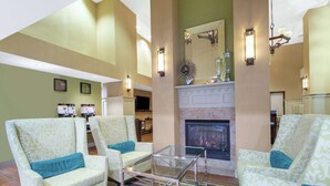 Un hall con sillones estampados, una mesa de centro de vidrio y una chimenea.