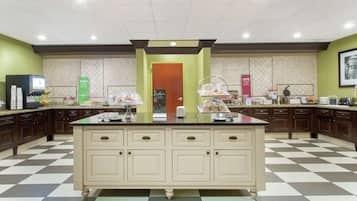 A kitchen with a checkered floor, a central island with a glass top, and various kitchen appliances and utensils.