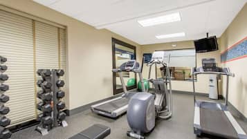 A gym with treadmills, elliptical machines, and a rack of dumbbells.