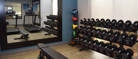 A gym with treadmills, a bench, and a rack of dumbbells.