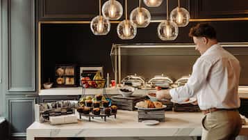 A buffet setup with various food items and a person serving.
