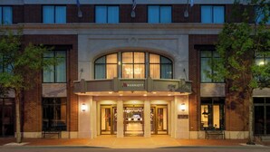 A Marriott hotel entrance with a brick facade, large arched windows, and a marquee sign above the doors.