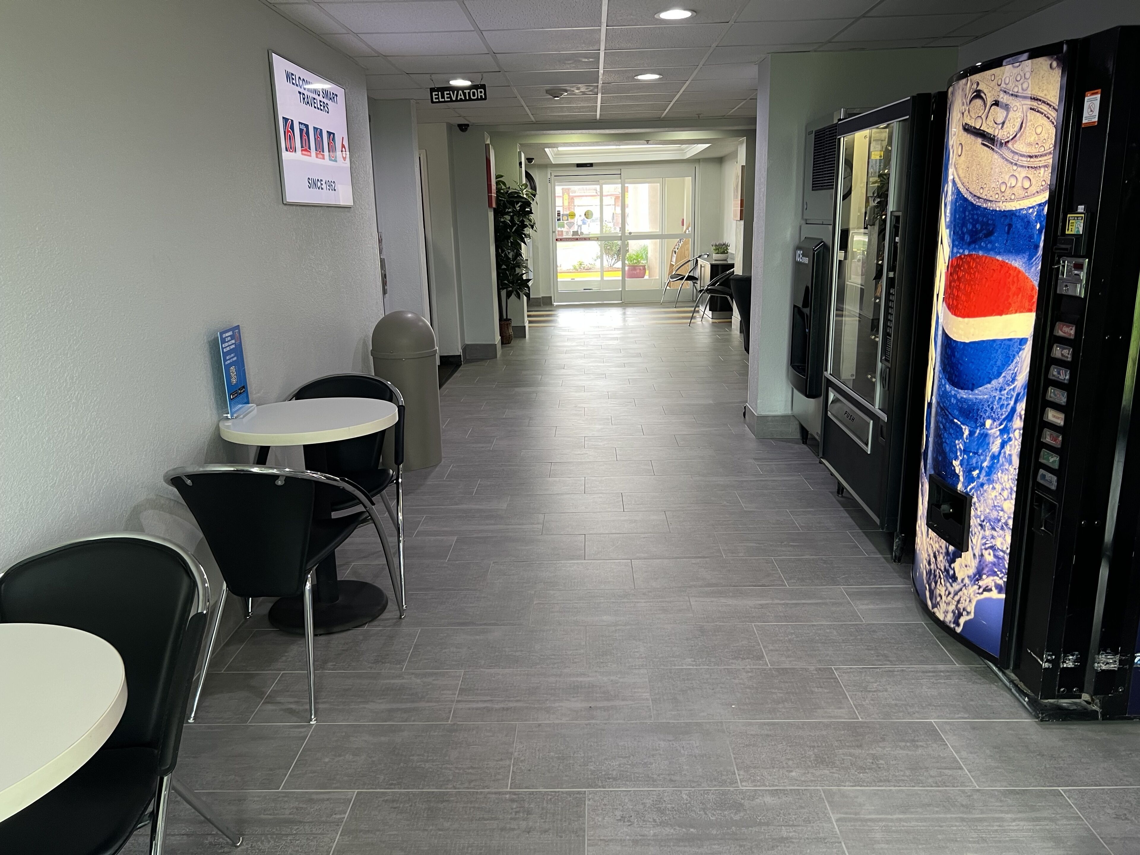 A hallway with a vending machine, a trash can, and a sign welcoming travelers.