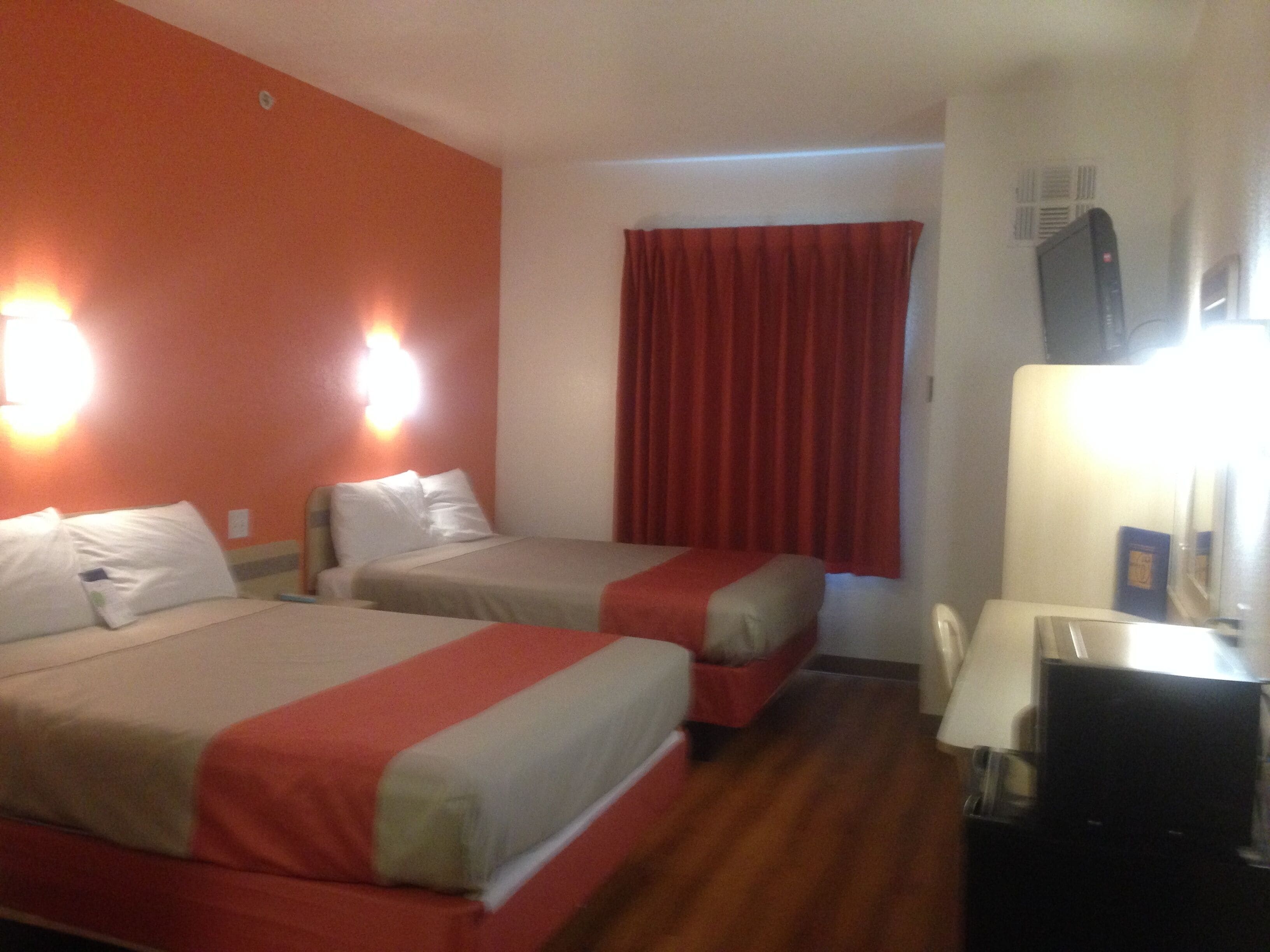 Habitación de hotel con dos camas, un escritorio y una televisión.